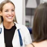 A doctor smiles at her patient in the foreground. Learn why DME compliance is key for healthcare professionals.